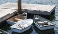 Three row boats with oars tied to a dock