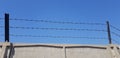 Three rows of barbed wire over gray concrete fence Royalty Free Stock Photo