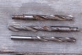 Three rusty drills on wooden background.