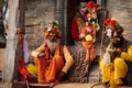 Three Sadhu dressed in saffron colored clothes sits in ancient votive shrine of Pandra Shivalaya Royalty Free Stock Photo