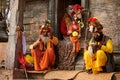 Three Sadhu dressed in saffron colored clothes sits in ancient votive shrine of Pandra Shivalaya Royalty Free Stock Photo