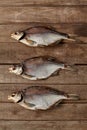 Three salted sun-dried breams on wooden planks background