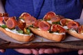 Three sandwiches with figs, smoked ham, arugula and soft cheese on a wooden board Royalty Free Stock Photo