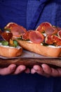 Three sandwiches with figs, smoked ham, arugula and soft cheese on a wooden board Royalty Free Stock Photo
