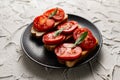 Three sandwiches with fresh and bright red tomatoes and smoked sausage, decorated with a leaf of green arugula Royalty Free Stock Photo