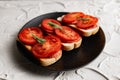 Three sandwiches with fresh and bright red tomatoes and smoked sausage, decorated with a leaf of green arugula Royalty Free Stock Photo