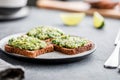 Three sandwiches with rye bread and mashed avocado on a plate