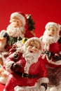 Three Santa Claus figurines over red background