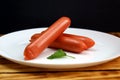 Three sausages lie on a white plate stacked in a pile Royalty Free Stock Photo