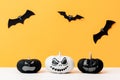 Three scary Black and White Jack o Lanterns and flying paper bats over yellow background. Halloween background.