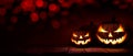 Three scary halloween lanterns with evil eyes and faces on a rustic wood table with a spooky dark red background Royalty Free Stock Photo