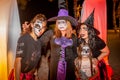 Three scary witches and little girl during Halloween party at the artificial cemetery on the beach