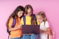 Three schoolgirls are looking at a laptop with enthusiasm. Distance learning concept