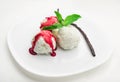 Three scoops of vanilla ice cream with strawberry syrup and mint on a white plate and a vanilla bean Royalty Free Stock Photo