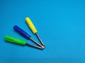 Three screwdrivers of different colors vertically on a blue background. copy space. Royalty Free Stock Photo