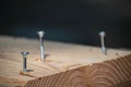 Three screws in wood half screwed in. Dark background. Craftmanship with wood construction. Royalty Free Stock Photo