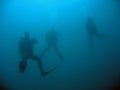 three scuba divers on deep dive