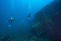Scuba divers simming near a shipwreck under the sea Royalty Free Stock Photo