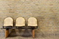 Three seated bench against yellow brick wall