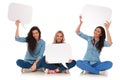 Three seated young women smile and hold blank speech bubbles