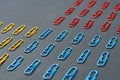 Three sections of rows of many red, yellow and blue colors paper clips for office work or education lies on dark scratched concret