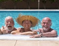 Three senior happy people having fun in the swimming pool under the sun - two brothers, facial expression, smiles and laugh Royalty Free Stock Photo