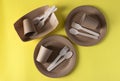 Three sets disposable biodegradable tableware of craft paper and wood - plates, forks, spoons, glasses on yellow