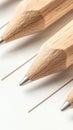 Three sharpened wooden pencils rest on lined paper, their tips angled towards the viewer. Royalty Free Stock Photo