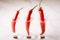 three shots of vodka and red pepper/three shots of vodka and red pepper on a white marble background. Selective focus