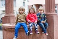 Three siblings sitting together on fountain in city Royalty Free Stock Photo