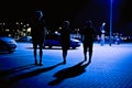 Three Silhouettes Walking In A Parking Lot With Deep Shadows