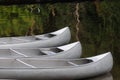 Three silver canoes on calm lake water Royalty Free Stock Photo