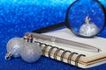 Three silver Christmas balls lie next to a notebook, magnifying glass and fountain pen. Examination, research and analysis of the