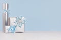 Three silver metallic gift boxes with shiny ribbons and bows on soft light white wood board and pastel blue wall. Royalty Free Stock Photo