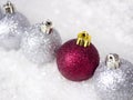 Three silver and one red Christmas balls in snow bokeh Royalty Free Stock Photo