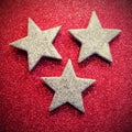 Three silver stars on red glittery texture