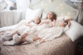 Three sisters in the bedroom in the morning. Girls in pajamas on the bed. Royalty Free Stock Photo