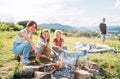 Three sisters cheerfully smiling while they roasting a marshmallows candies on the sticks over the campfire flame. Happy family