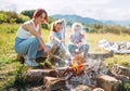 Three sisters cheerfully smiling while they roasting a marshmallows candies on the sticks over the campfire flame. Happy family