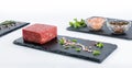 Three slate boards with piece of raw ground beef, whole pepper,