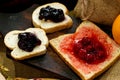 Three Slices of Baked Bread with Sweet Strawberry and Blueberry Jam on rustic wooden board Royalty Free Stock Photo