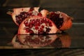 Three slices of the cut pomegranate lie on a wooden board. Dark background Royalty Free Stock Photo