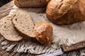 Three slices of fresh crusty bread on a rustic cloth and wooden background with a knife on the side