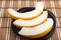 Three slices of juicy yellow melon on a black plate Royalty Free Stock Photo