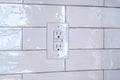 Three slot grounded receptacle for electric appliances on tiled wall of home