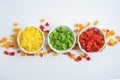 Three small bowls of chopped paprika with spread pieces of mixed paprika on the background