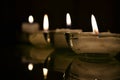 Three small flat candlesticks with burning white candles on a dark background in a dark room 2 Royalty Free Stock Photo