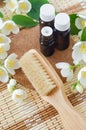 Three small glass bottles with essential jasmine oil tincture, infusion, perfume, wooden body brush and jasmine flowers.