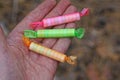 three small long candies in colored transparent packaging lie on the fingers