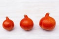 Three small pumpkins in row on white wooden table. Autumn decoration and seasonal vegetables on wood. Royalty Free Stock Photo